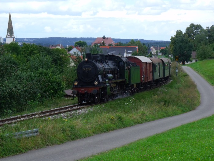 38&nbsp;3199 mit Zug nach Neuffen, kurz hinter Linsenhofen, wovon im Hintergrund der Haltepunkt zu sehen ist, um  13:32h am 21.08.2016