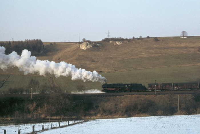 044&nbsp;195&nbsp;Tv schiebt hier einen von der 050&nbsp;737 gezogenen Güterzug aus Northeim nach Ellrich die bekannte Osterhagener Rampe bei Bartolfelde hoch, 17:15h am 19.03.1976