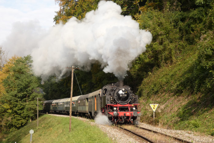 64&nbsp;419 mit Zug Schorndorf&rarr;Welzheim (hinten Schub: V100), am Landstraßen-Bahnübergang hinterm Strümpfelbachtal, um 11:10h am 17.10.2021