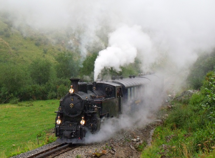 FO&nbsp;4 mit Zug Realp-Oberwald, im Furkareusstal unterhalb vom Haltepunkt Tiefenbach im heftigen und strömenden Regen, den man hier auch deutlich sehen kann, um 10:34h am 15.08.2015