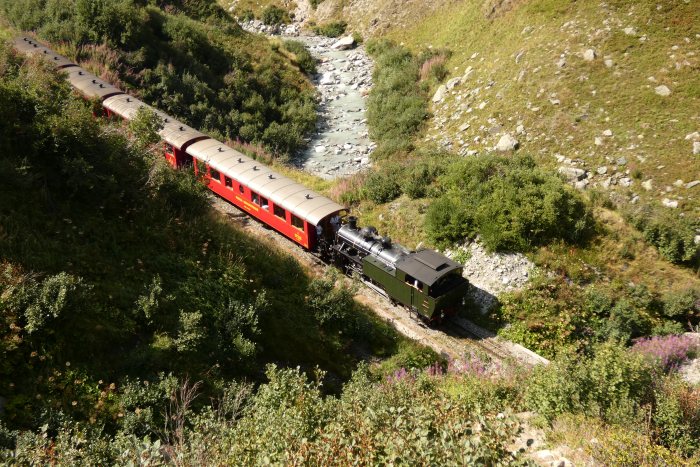Lok 704&nbsp;Tv vor dem Zug Nr.154 Oberwald&rarr;Realp abwärts fahrend unterhalb vom Alt-Senntumstafel-Tunnel&nbsp;II, um 15:44h am 12.08.2022