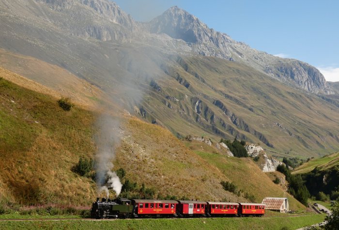 704&nbsp; mit Zug Nr.133 Realp->Oberwald auf dem Bahndamm am Nordhang vor den Wilerbrücken, um 10:27h am 13.08.2022