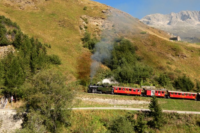 704&nbsp; mit Zug Nr.133 Realp->Oberwald auf dem Bahndamm am Nordhang vor den Wilerbrücken, um 10:27h am 13.08.2022
