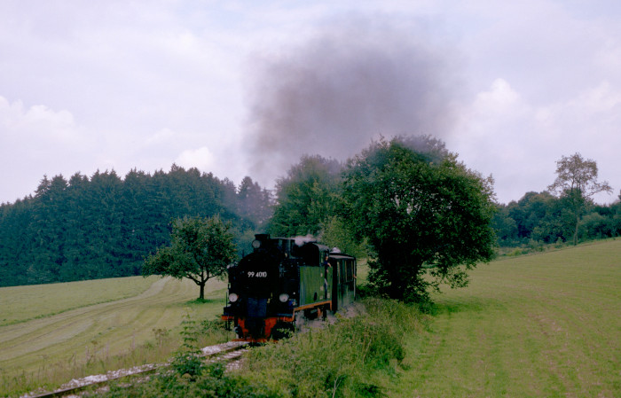 Lok Nr.10 als &bdquo;99&nbsp;4010&ldquo; mit Regelzug auf der schwäbischen &bdquo;Öchsle&ldquo;-Bahn von Ochsenhausen kommend Richtung Warthausen ziemlich schnell und lautstark in der Steigung hinter Reinstetten einige hundert Meter vor dem Scheitelpunkt der Bahn, fotografiert und aufgenommen am 22.09.1996 um 14:20h