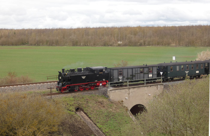 Lok&nbsp;11&nbsp; mit Infozug zurück &rarr;Benndorf in der Senke der MBB-Strecke nahe der Niewandtschachthalde, fotografiert von weiter oben auf der Halde stehend, um 13:07h am 01.04.2023
