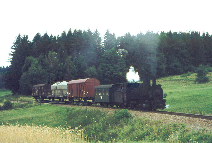 399.04 mit einem der typischen und schwer aussehenden Güterzüge nahe der Schleife bei Weitra, fotografiert im Juli&nbsp;1976