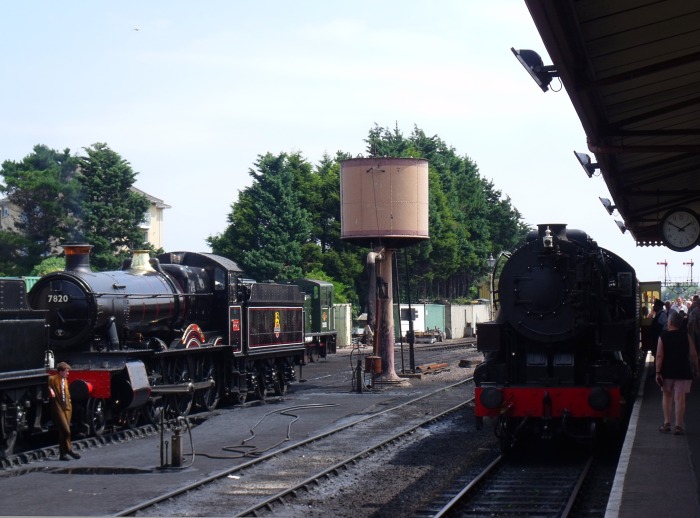 Rechts ist 6046 ist mit ihrem Zug von Bishops Lydeard eingetroffen, links sieht man in Mi&zwj;n&zwj;ehead  die 7820 DINMORE&nbsp;MANOR (hinter dem Tender der 7822 FOXCOTE&nbsp;MANOR) stehen, fotografiert um 13:50h am 26.07.2018